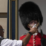 
              A police officer givers water to a British soldier wearing a traditional bearskin hat, on guard duty outside Buckingham Palace, during hot weather in London, Monday, July 18, 2022. The British government have issued their first-ever "red" warning for extreme heat. The alert covers large parts of England on Monday and Tuesday, when temperatures may reach 40 degrees Celsius (104 Fahrenheit) for the first time, posing a risk of serious illness and even death among healthy people, the U.K. Met Office, the country's weather service, said Friday. (AP Photo/Matt Dunham)
            