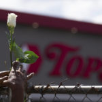 
              Cariol Horne, 54, places a rose on the fence outside the Tops Friendly Market on Thursday, July 14, 2022, in Buffalo, N.Y. The Buffalo supermarket where 10 Black people were killed by a white gunman is set to reopen its doors, two months after the racist attack. (AP Photo/Joshua Bessex)
            