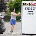 
              A woman drops a ballot into a drop box while casting her vote during Maryland's primary election, Tuesday, July 19, 2022, in Baltimore. (AP Photo/Julio Cortez)
            