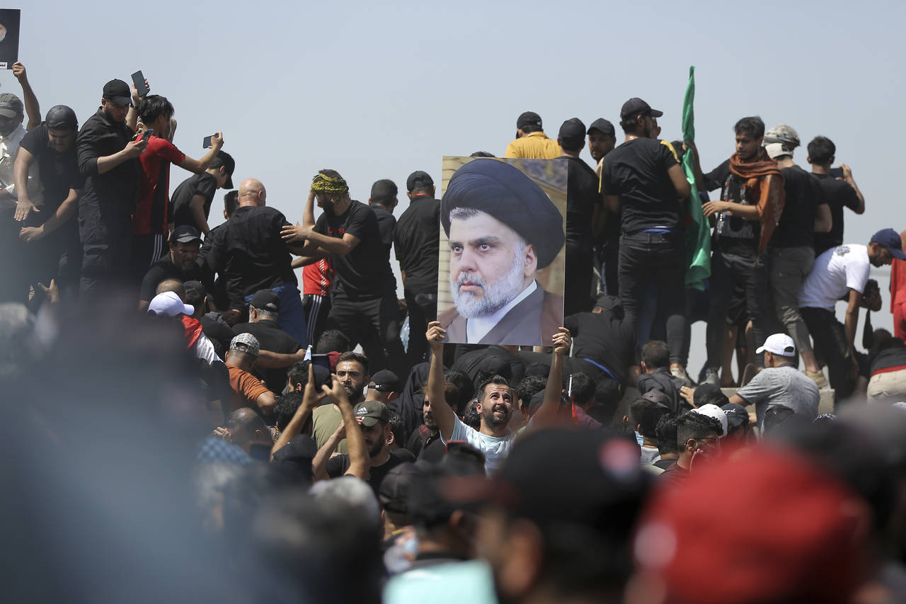 A protester holds a poster depicting Shiite cleric Muqtada al-Sadr on a bridge leading towards the ...