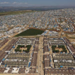 
              FILE - An aerial view shows a large refugee camp on the Syrian side of the border with Turkey, near the town of Atma, in Idlib province, Syria, April 19, 2020. Syrians in the last major rebel stronghold in the war-ton country are living in fear of the effects of Russia closing down the only border crossing into the northwestern province of Idlib. Aid agencies warn that if Russia vetoes the resolution that would maintain two border crossing points from Turkey to deliver humanitarian aid, food would be depleted in Idlib and surrounding areas by September, 2022, putting the lives of some 4.1 million people, at risk. (AP Photo/Ghaith Alsayed, File)
            