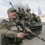 
              FILE - A pro-Russian separatist clears the way for a combat vehicle in Slovyansk, Ukraine, Wednesday, April 16, 2014. The eastern Ukrainian city of Slovyansk was occupied by pro-Russian separatists for months in 2014. Now its people are preparing to defend their community again as the fighting draws closer and invites a major battle. Slovyansk is a city of splintered loyalties, with some residents antagonistic toward Kyiv or nostalgic for their Soviet past. (AP Photo/Efrem Lukatsky, File)
            