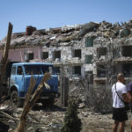
              Local residents stand next to damaged residential building in the town of Serhiivka, located about 50 kilometers (31 miles) southwest of Odesa, Ukraine, Friday, July 1, 2022. Russian missile attacks on residential areas in a coastal town near the Ukrainian port city of Odesa early Friday killed at least 19 people, authorities reported, a day after Russian forces withdrew from a strategic Black Sea island. (AP Photo/Nina Lyashonok)
            
