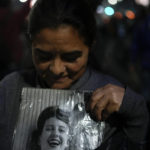 
              A woman holds a photo of Argentina's late former first lady Maria Eva Duarte de Peron, better known as "Evita" as people gather to honor her outside the Ministry of Social Development in Buenos Aires, Argentina, Tuesday, July 26, 2022. Argentines commemorate the 70th anniversary of the death of their most famous first lady Evita who died of cancer on July 26, 1952, at the age of 33. (AP Photo/Natacha Pisarenko)
            