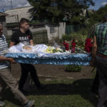 
              Men carry the lifeless body of 35-year-old Anna Protsenko, who was killed in a Russian rocket attack, during her funeral procession, on the outskirts of Pokrovsk, eastern Ukraine, Monday, July 18, 2022. (AP Photo/Nariman El-Mofty)
            