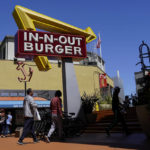 
              Pedestrians walk below an In-N-Out Burger restaurant sign in San Francisco, Thursday, Aug. 25, 2022. More than a half-million California fast food workers are pinning their hopes on a groundbreaking proposal that would give them increased power and protections. (AP Photo/Jeff Chiu)
            