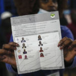 
              An election official holds up ballots for other officials and party agents to see, as they start to count votes at a polling station in Kilimera Primary School in Nairobi, Kenya, Tuesday, Aug. 9, 2022. Polls opened Tuesday in Kenya's unusual presidential election, where a longtime opposition leader who is backed by the outgoing president faces the deputy president who styles himself as the outsider. (AP Photo/Mosa'ab Elshamy)
            