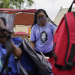 
              Nikiesha Thomas' sister Keeda Simpson wears a T-shirt with an image of her sister as she hands out donated school supplied during a Back To School Block Party in the Robinwood Community of Annapolis, Md., Sunday, Aug. 21, 2022. The block party was hosted by Beacon Light Seventh-day Adventist Church, and sponsored by the Nikiesha Thomas Memorial and Allstate Insurance. Nikiesha Thomas was shot and killed by her ex-boy boyfriend just days after filing for a protective order. (AP Photo/Carolyn Kaster)
            