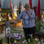 
              Hanna, 62, cries at the grave or her son Shufryn Andriy, 41, a Ukrainian serviceman who died in the war against Russia, at the cemetery in Lviv, Ukraine, Saturday, Aug. 27, 2022. (AP Photo/Emilio Morenatti)
            