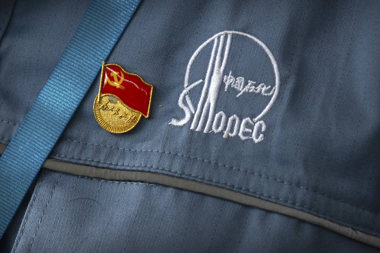 FILE - A Chinese Communist Party badge is pinned to a worker's uniform at the Sinopec Yanshan Petro...