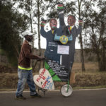 
              A supporter of Kenya's President-elect William Ruto pushes a cart with cardboard cutout of the president and his running mate, outside the official residence of the deputy president in the Karen area of Nairobi, Kenya Wednesday, Aug. 17, 2022. (AP Photo/Mosa'ab Elshamy)
            