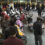 
              FILE - Residents watch a convoy of security personnel armed with batons and shields patrol through central Kashgar in western China's Xinjiang region, Nov. 5, 2017. China's discriminatory detention of Uyghurs and other mostly Muslim ethnic groups in the western region of Xinjiang may constitute crimes against humanity, the U.N. human rights office said in a long-awaited report Wednesday, Aug. 31, 2022, which cited "serious" rights violations and patterns of torture in recent years. (AP Photo/Ng Han Guan, File)
            
