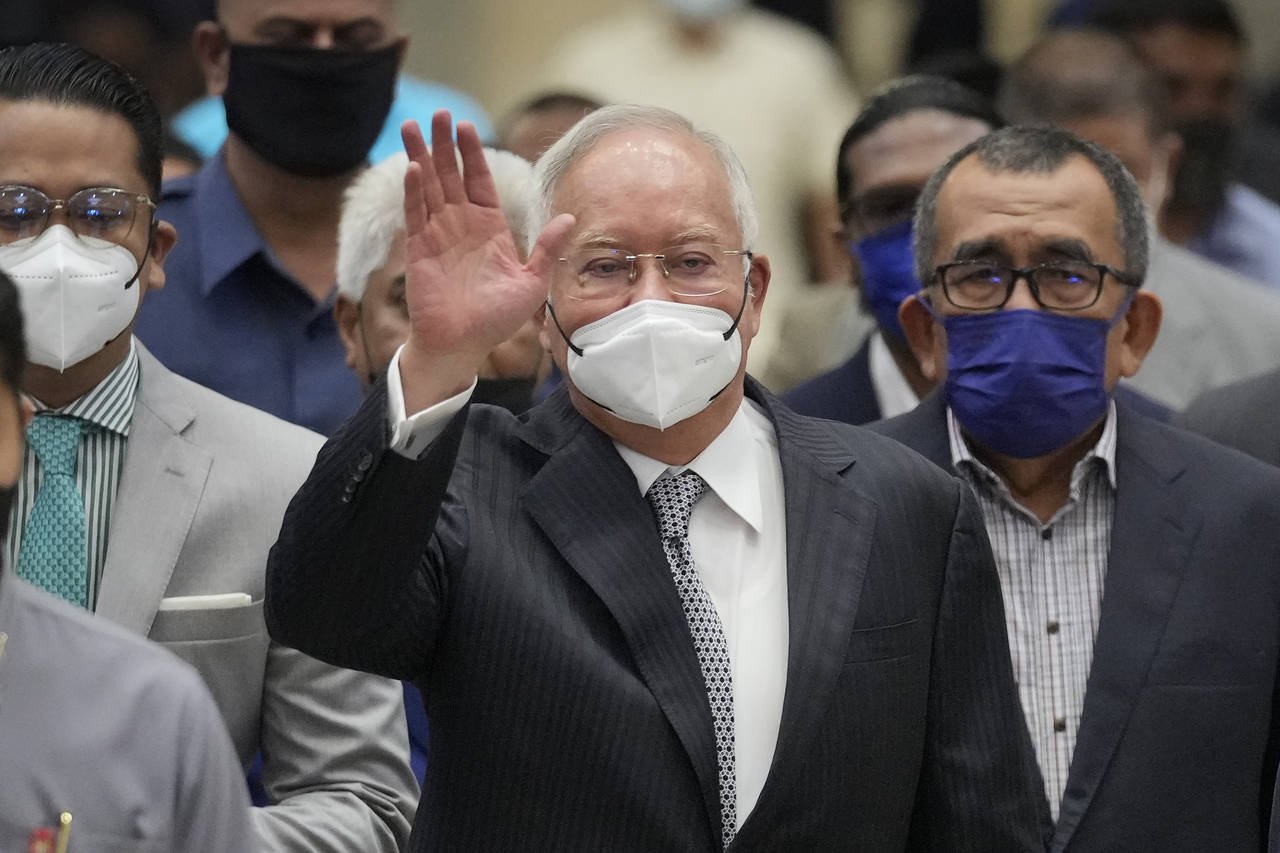 FILE - Former Malaysian Prime Minister Najib Razak, center, wearing a face mask, waves as he arrive...