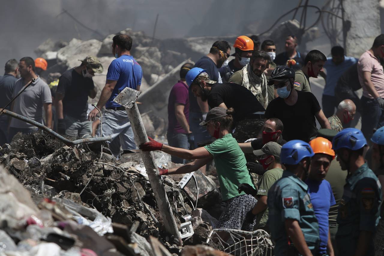 Armenian emergency employees and volunteers work on the side of burned Surmalu market about two kil...