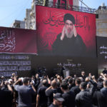 
              Hezbollah leader Sheik Hassan Nasrallah, greats his supporters as he speaks via a video link, during the holy day of Ashoura that commemorates the 7th century martyrdom of the Prophet Muhammad's grandson Hussein, in the southern suburb of Beirut, Lebanon, in Beirut, Lebanon, Tuesday, Aug. 9, 2022. The leader of Lebanon’s militant Hezbollah group has issued warning to archenemy Israel over the two countries' maritime border dispute. (AP Photo/Hussein Malla)
            