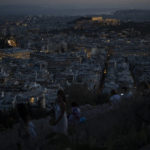 
              People admire the view of the city of Athens with the Greek Parliament on the left and the ancient Acropolis hill on the right, Wednesday , Aug. 10 , 2022.The European Union's budget watchdog announced Wednesday that it is winding up years of surveillance of Greek government spending. The move marks a formal end to a major crisis that threatened to see Greece ejected from the euro single currency group, imposed severe hardship on its citizens and roiled global financial markets. (AP Photo/Petros Giannakouris)
            