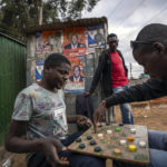 
              Men play a board-game on a street in the Kibera area of Nairobi, Kenya Friday, Aug. 12, 2022. Vote-tallying in Kenya's close presidential election isn't moving fast enough, the electoral commission chair said Friday. (AP Photo/Ben Curtis)
            