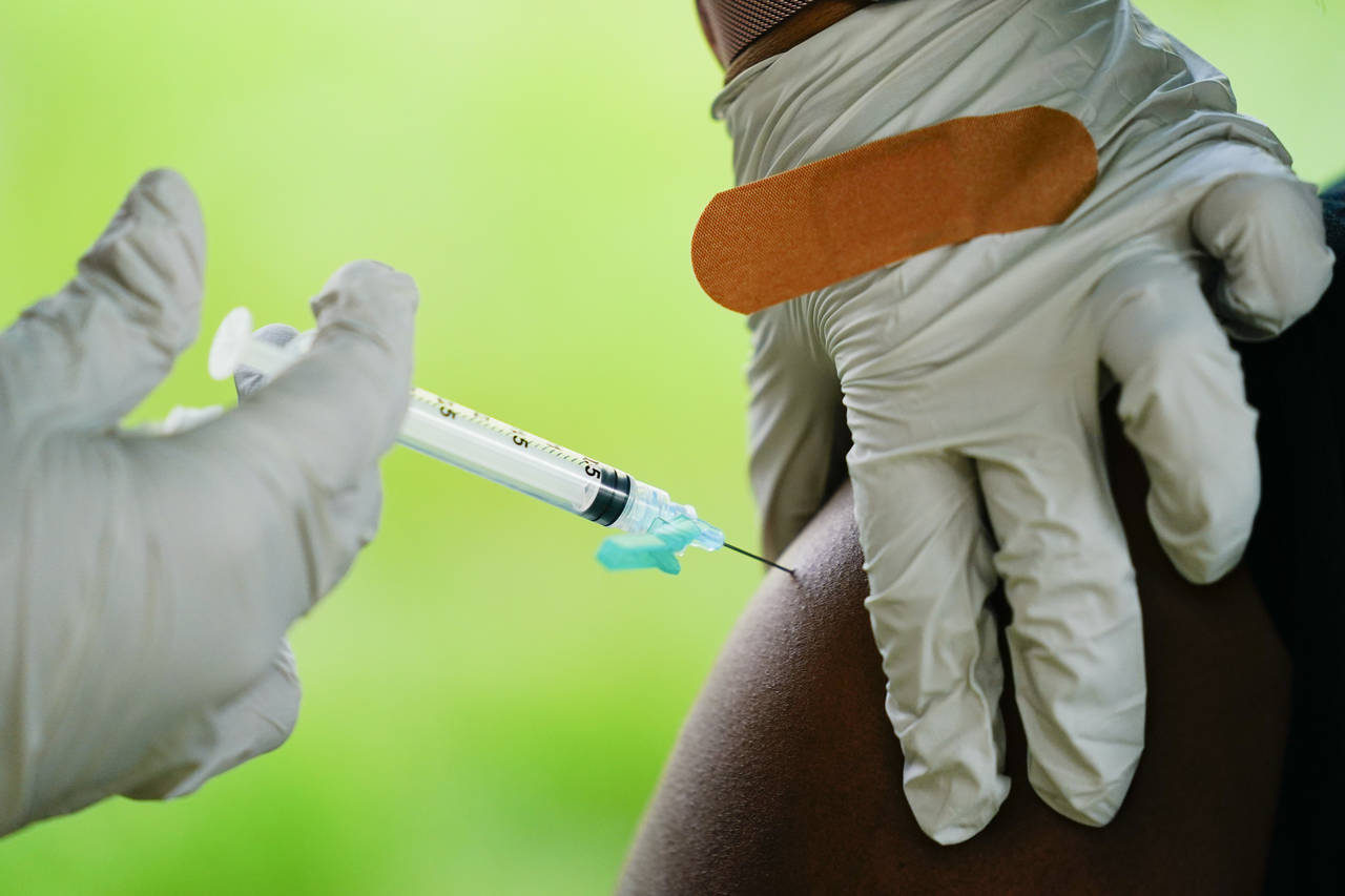 FILE - A health worker administers a dose of a Pfizer COVID-19 vaccine during a vaccination clinic ...