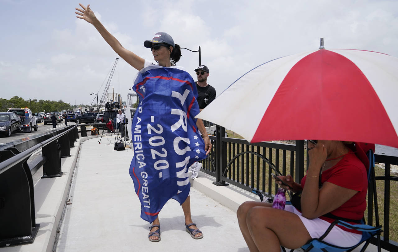 A Donald Trump supporter stands on a bridge outside the entrance to former President Donald Trump's...