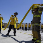 
              Cadets, who were formerly-incarcerated firefighters load a fire hose onto a fire truck at the Ventura Training Center (VTC) during an open house media demonstration on Thursday, July 14, 2022, in Camarillo, Calif. California has a first-in-the nation law and a $30 million training program both aimed at trying to help former inmate firefighters turn pro after they are released from prison. The 18-month program is run by Cal Fire, the California Conservation Corps, the state corrections department and the nonprofit Anti-Recidivism Coalition at the Ventura Training Center northwest of Los Angeles. (AP Photo/Damian Dovarganes)
            