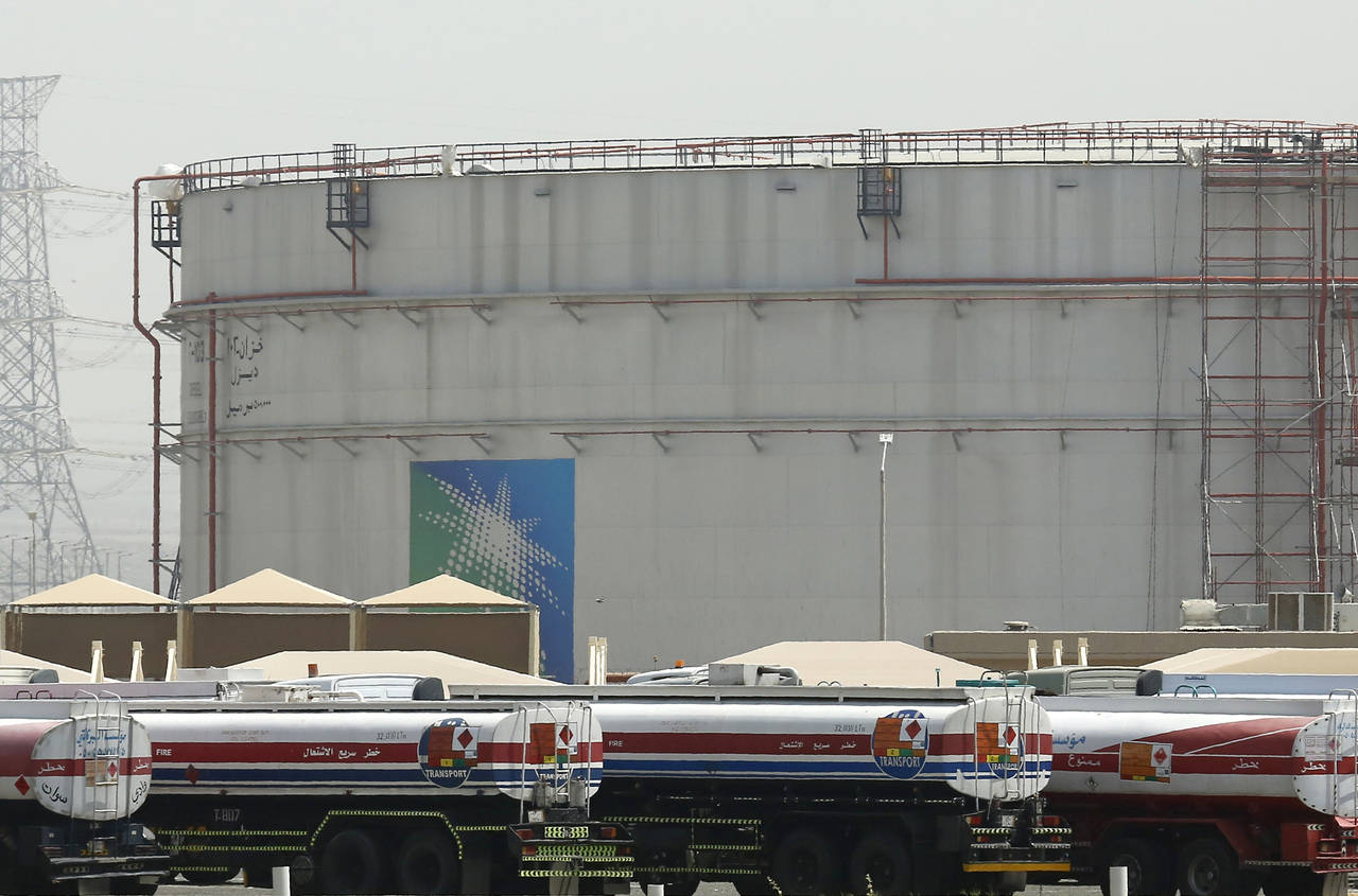 FILE - Fuel trucks line up in front of storage tanks at the North Jiddah bulk plant, an Aramco oil ...