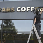 
              A worker removes a cover from the name of a newly opened Stars Coffee coffee shop in the former location of the Starbucks coffee shop in Moscow, Russia, Thursday, Aug. 18, 2022. A new chain of coffee shops opens Thursday in Moscow, after Russian singer and entrepreneur Timur Yunusov, better known as Timati, together with Russian restaurateur Anton Pinskiy bought the Starbucks stores following company's withdrawal from Russia. (AP Photo/Dmitry Serebryakov)
            