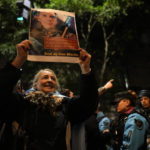 
              A woman who is against Argentine Vice President Cristina Fernandez holds a picture of prosecutor Diego Luciani outside Cristina Fernandez's home in Buenos Aires, Argentina, Monday, Aug. 22, 2022, Prosecutors asked a judge to sentence Fernández to 12 years in prison and bar her from holding public office for life for allegedly leading a criminal conspiracy that irregularly awarded public works contracts to a friend and ally. (AP Photo/Natacha Pisarenko)
            