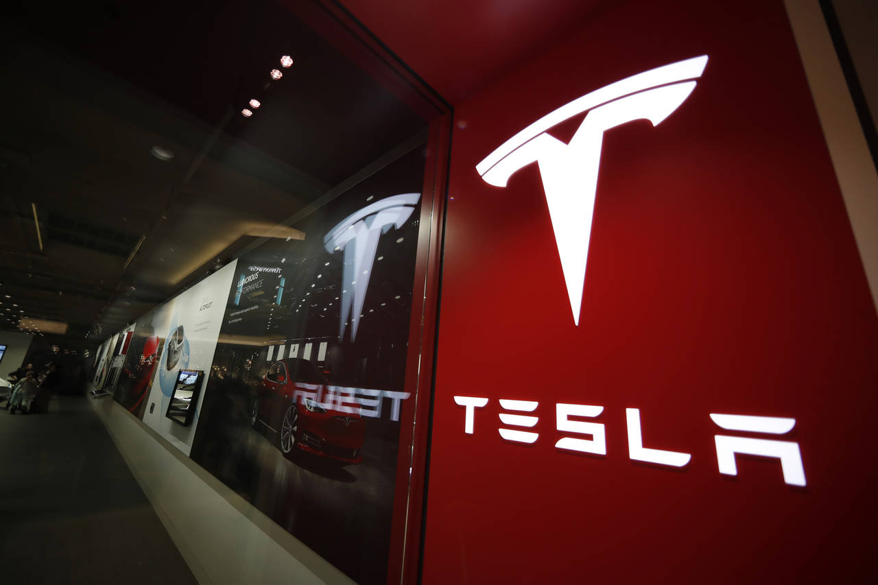 FILE - A sign bearing the company logo outside a Tesla store in Cherry Creek Mall in Denver is seen...