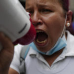 
              A nurse uses a megaphone during a protest by active and retired public workers demanding the government pay their full benefits and respect collective bargaining agreements, in Caracas, Venezuela, Tuesday, Aug. 23, 2022. (AP Photo/Ariana Cubillos)
            