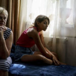 
              Anastasiia Aleksandrova, 12, right, sits with her grandmother, Olena, at their home in Sloviansk, Donetsk region, eastern Ukraine, Monday, Aug. 8, 2022. With cities largely emptied after hundreds of thousands have evacuated to safety, the young people that remain face alienation, loneliness and boredom as unlikely yet painful counterpoints to the fear and violence Moscow has unleashed on Ukraine. (AP Photo/David Goldman)
            