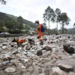 
              In this photo released by Xinhua News Agency, a rescue worker and dog search through the aftermath of floods in Shadai Village, Qingshan Township of Datong Hui and Tu Autonomous County in northwest China's Qinghai Province on Thursday, Aug. 18, 2022. A sudden rainstorm in western China triggered a landslide that diverted a river and caused flash flooding in populated areas, killing some and leaving others missing, Chinese state media said Thursday. (Zhang Hongxiang/Xinhua via AP)
            