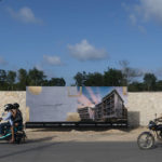 
              People ride their motorcycles past an advertisement that offers modern condominiums for sale, next to a squatters' settlement known as October 2, in Tulum, Quintana Roo state, Mexico, Thursday, Aug. 4, 2022. Condos on the edge of the squatters´ camp, and some well inside it, now sell for between $100,000 and $150,000 and are advertised in U.S. dollars, as are entrance fees at many seaside resorts.  (AP Photo/Eduardo Verdugo)
            