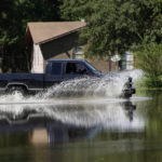 
              A homeowner rushes through rising floodwaters in this northeast Jackson, Miss., neighborhood, Sunday, Aug. 28, 2022. Local officials anticipate flooding in neighborhoods near the Pearl River, the results of severe flooding from heavy rains days earlier. (AP Photo/Rogelio V. Solis)
            