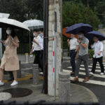 
              Office workers walk with umbrellas during a rainy day in Beijing, Thursday, Aug. 18, 2022. Some were killed with others missing after a flash flood in western China Thursday, as China faces both summer rains and severe heat and drought in different parts of the country. (AP Photo/Ng Han Guan)
            
