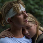 
              Nelia Fedorova, left, is embraced by her daughter, Yelyzaveta Gavenko, 11, as they visit a neighbor's home where someone was killed in a Russian rocket attack Friday night which also injured Federova, in Kramatorsk, Donetsk region, eastern Ukraine, Saturday, Aug. 13, 2022. The strike killed three people and wounded 13 others, according to the mayor. The attack came less than a day after 11 other rockets were fired at the city. (AP Photo/David Goldman)
            