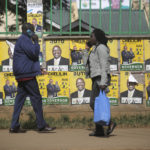 
              People walk in front of election posters in Eldoret, Kenya, Wednesday Aug. 10, 2022. Kenyans are waiting for results in the presidential elections that saw opposition leader Raila Odinga face Deputy President William Rutoto in their bid to succeed President Uhuru Kenyatta who stayed in power for a decade. (AP Photo/Brian Inganga)
            