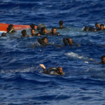 
              People swim next to their overturned wooden boat during a rescue operation by Spanish NGO Open Arms at south of the Italian Lampedusa island at the Mediterranean sea, Thursday, Aug. 11, 2022. Forty migrants from Eritrea and Sudan, two children and one woman, were rescued by NGO Open Arms crew members and Italian coast guard after their boat overturned and started to sink. (AP Photo/Francisco Seco)
            