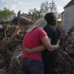 
              Ukrainian women hug in front of a building destroyed during a missile strike in Kharkiv, Ukraine, Thursday, Aug. 18, 2022. (AP Photo/Andrii Marienko)
            