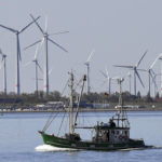
              FILE - A fisher boat passes wind turbines between the island Langeoog and Bensersiel at the North Sea coast in Germany, on May 15, 2019. Denmark will increase a planned offshore wind capacity in the Baltic Sea to 3 gigawatts and hook it up to the German grid which will be a step toward weaning Europe off its reliance on Russian gas. The deal was announced Monday Aug. 29, 2022 in Copenhagen. (AP Photo/Martin Meissner, File)
            