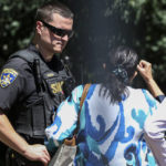 
              An officer with the Chautauqua Sheriff's Department speaks to a person at the Chautauqua Institution in Chautauqua, N.Y., Friday, Aug. 12, 2022. Salman Rushdie, the author whose writing led to death threats from Iran in the 1980s, was attacked and apparently stabbed in the neck Friday by a man who rushed the stage as he was about to give a lecture at the Chautauqua Institution. (AP Photo/Joshua Bessex)
            