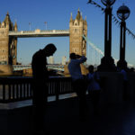 
              A tourist checks his mobile as others take photographs of Tower Bridge on South banks on the river Thames, in London, England, Thursday, Aug. 11, 2022. Heatwaves and prolonged dry weather are damaging landscapes, gardens and wildlife, the National Trust has warned. Britain is braced for another heatwave that will last longer than July's record-breaking hot spell, with highs of up to 35 degrees Celsius expected next week. (AP Photo/Manish Swarup)
            
