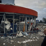 
              People stand in front of destroyed buildings after the Russian shelling in Mykolaiv, Ukraine, Wednesday, Aug. 3, 2022. According local media, supermarket, high-rise buildings and pharmacy were damaged. (AP Photo/Kostiantyn Liberov)
            