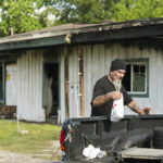 
              Robin Ahrens, a resident of a multi-room renting facility, walks past the burned out building in the aftermath of a fatal shooting in Houston on Sunday, Aug. 28, 2022. A longtime tenant started several fires at the site early Sunday and then shot at residents as they fled the blaze, before authorities fatally shot him, police said. (Brett Coomer/Houston Chronicle via AP)
            
