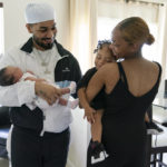 
              Aaliyah Wright, 25, of Washington, right, holds their son Khaza, 1, as she greets her husband Kainan Wright, 24, of Washington, holding their newborn daughter Kali, during a visit to the children's grandmother in Accokeek, Md., Tuesday, Aug. 9, 2022. A landmark social program is being pioneered in the nation’s capital. Coined “Baby Bonds,” the program is designed to narrow the wealth gap. The program would provide children of the city’s poorest families up to $25,000 when they reach adulthood. (AP Photo/Jacquelyn Martin)
            