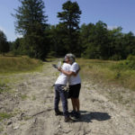 
              Gail Melix, of Barnstable, Mass., right, a member of the Herring Pond Wampanoag tribe, hugs a volunteer, left, as they pause while working to remove invasive plant species at the Wampanoag Common Lands project, in Kingston, Mass., Tuesday, Aug. 2, 2022. The project by the Native Land Conservancy is among efforts by tribes and other Native groups nationwide to reclaim and repair lands altered by western civilization. (AP Photo/Steven Senne)
            