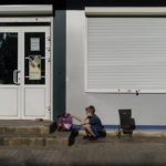 
              A child waits for his mother outside one of the few shops still open in Sloviansk, Donetsk region, eastern Ukraine, Saturday, Aug. 6, 2022. Of the roughly 275,000 children aged 17 or younger in the Donetsk region before Russia's invasion, around 40,000 remain, the province's regional governor Pavlo Kyrylenko told The Associated Press in an interview. (AP Photo/David Goldman)
            