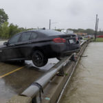 
              A car sits on the rail overlooking the flooded South Mesquite River on Monday, Aug. 22, 2022, in Mesquite, Texas. The National Weather Service issued a flash flood warning early Monday morning which was extended until 1 p.m. (Juan Figueroa/The Dallas Morning News via AP)
            
