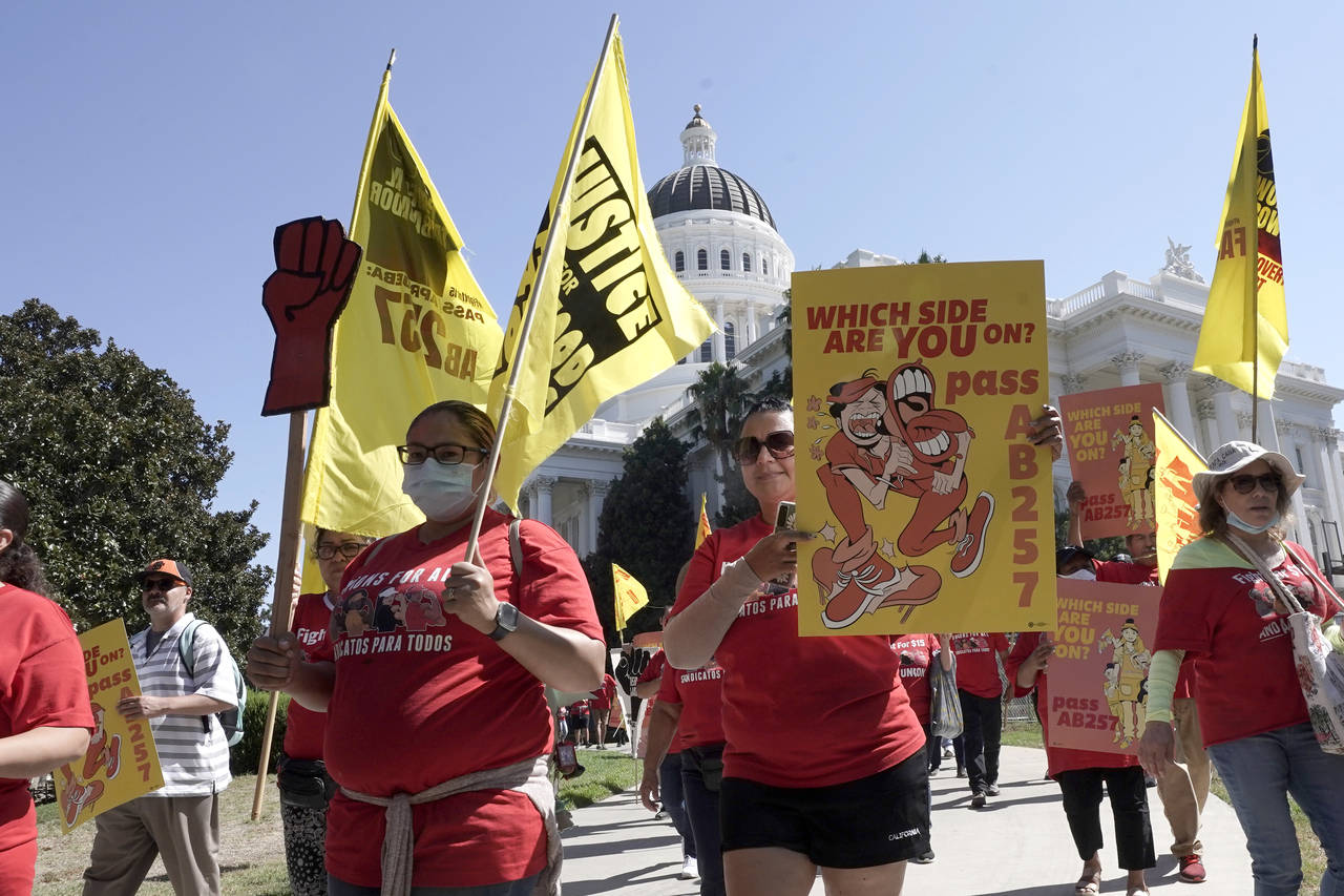 Fast food workers and their supporters march past the state Capitol calling on passage of a bill to...