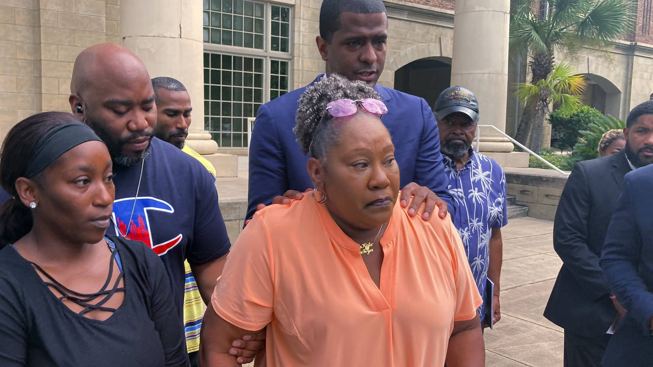 Betty James, center, is comforted by one of her attorneys, Bakari Sellers (standing behind her with...