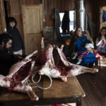 
              Millaray Huichalaf, a Mapuche machi, or healer and spiritual guide, cradles her 2-year-old daughter, Anukeu, as her brother prepares racks of lamb for celebrations of We Tripantu, the Mapuche new year, at her home in Carimallin, southern Chile, Saturday, on June 25, 2022. "In addition to being a healer, I'm also a militant in Mapuche resistance. Every day that I wake up, I think about how I can keep defending the river," Huichalaf says. She also hopes her daughters will continue the fight. (AP Photo/Rodrigo Abd)
            
